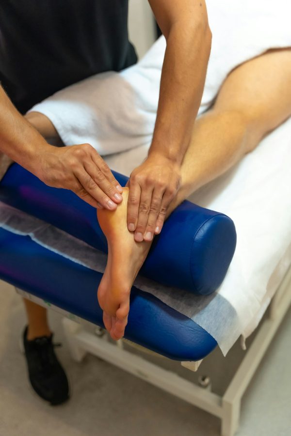 Vertical shot of a Physiotherapist doing a therapeutic massage to the client's ankle